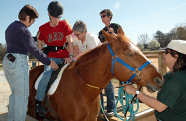 volunteers helping student on a horse