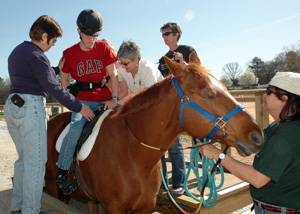 volunteers helping student on a horse