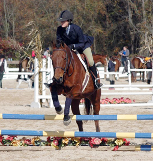 student jumping fence on horse